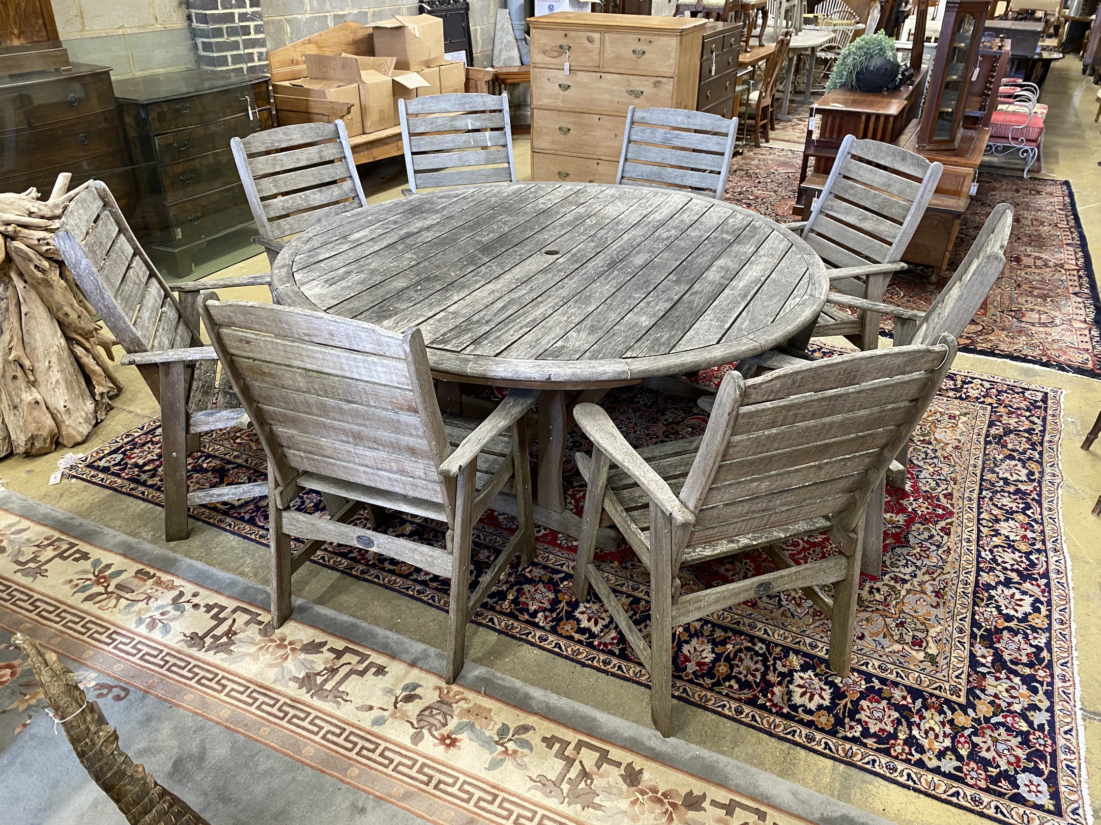 Lazy Dayz, New Zealand, a circular teak garden table, diameter 180cm, height 72cm and eight elbow chairs